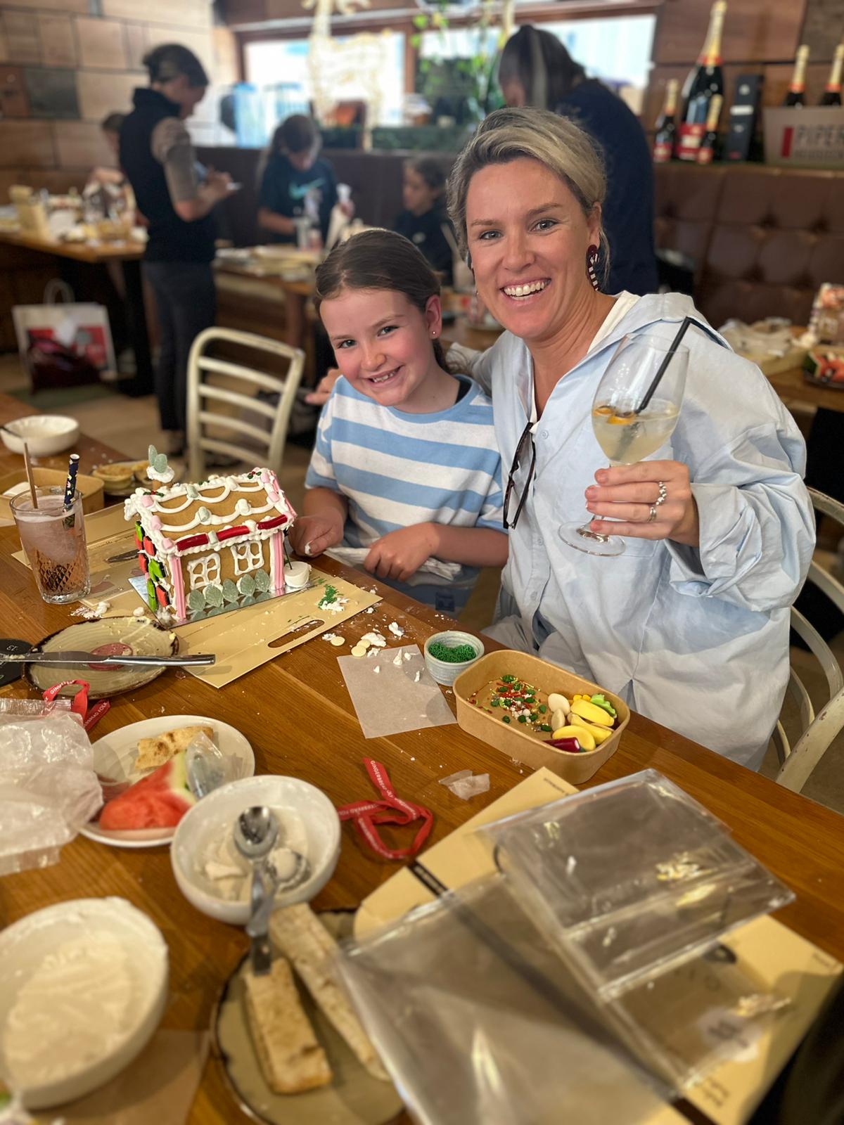 An adult and child decorating a gingerbread house together at Henry and the Fox