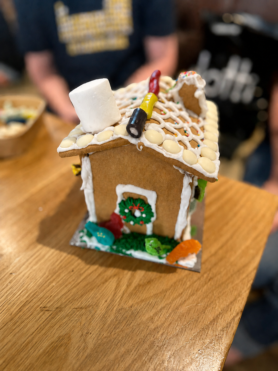 A completed gingerbread house decorated with icing and lollies